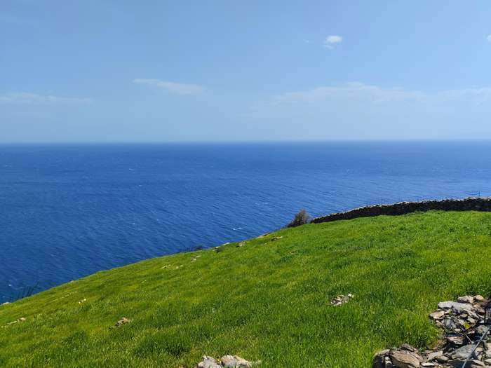 countyside landscape with a meadow, an old stone fence and sea with blue sky in the background
